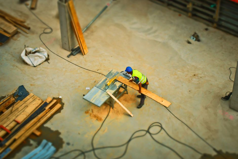 Construction worker cutting timber on a job site
