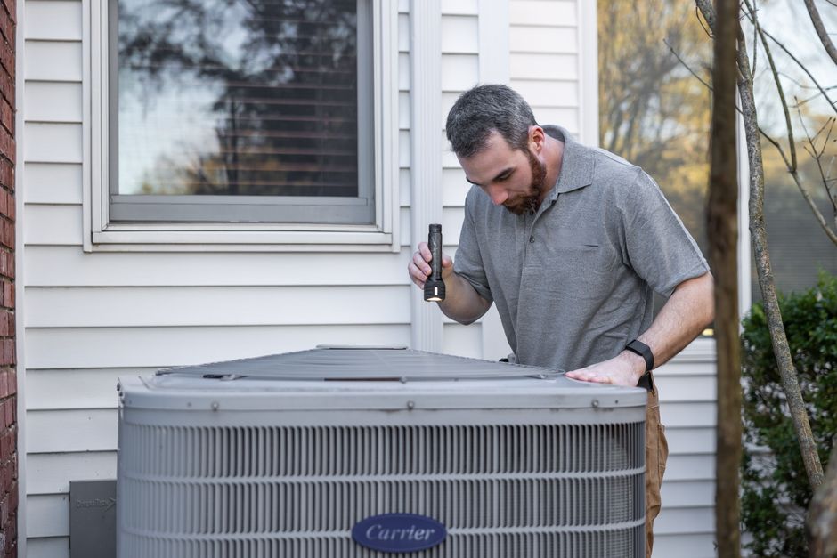 Technician inspecting an outdoor HVAC unit